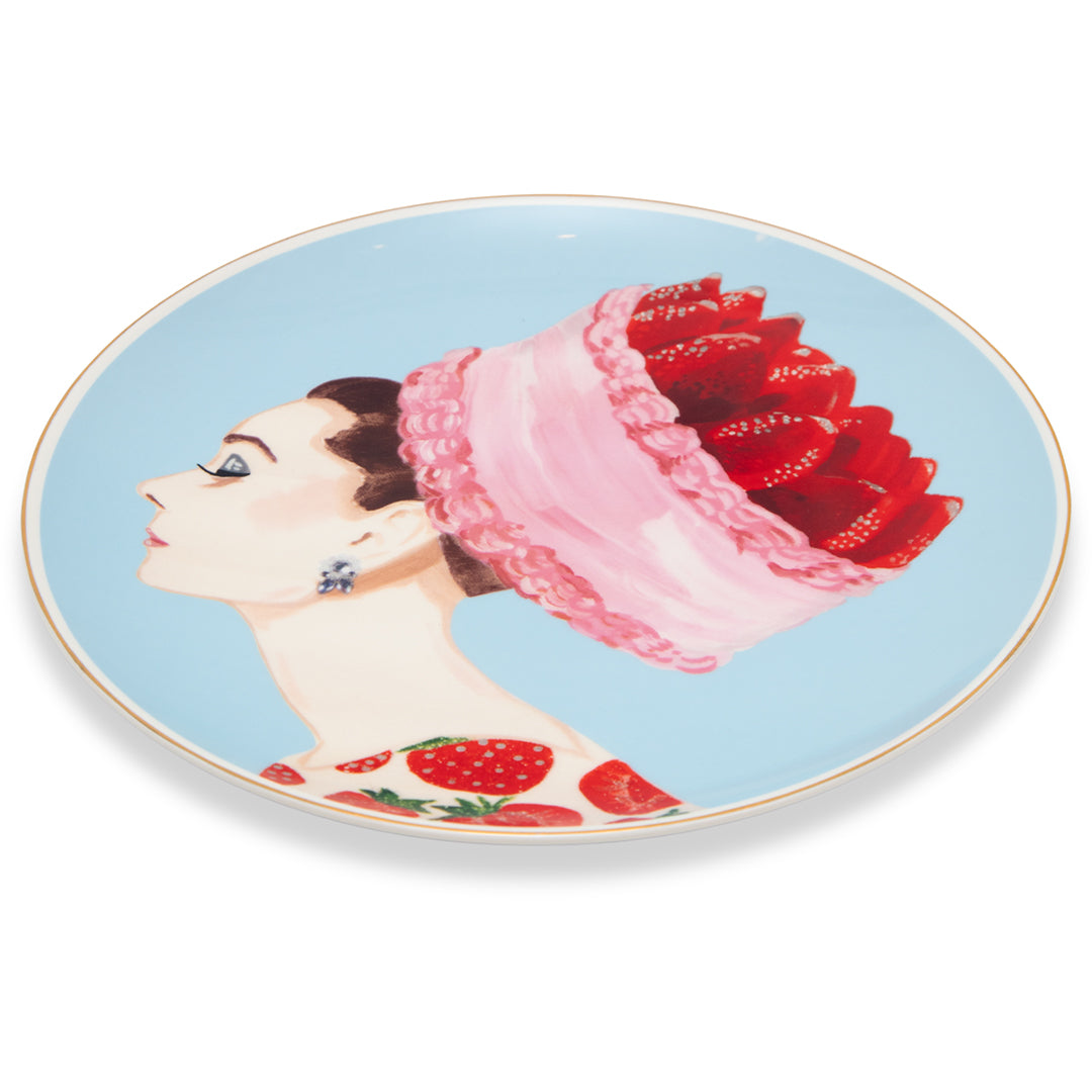 Ashley Longshore decorative porcelain platter featuring a painting of Audrey Hepburn with a strawberry cake chapeau on a blue background.