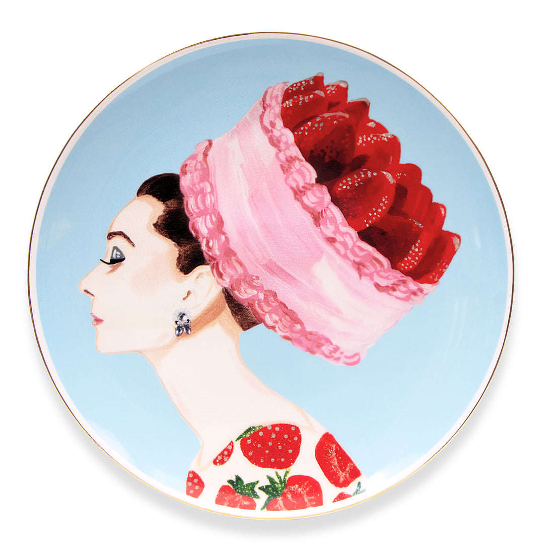 Ashley Longshore decorative porcelain platter featuring a painting of Audrey Hepburn with a strawberry cake chapeau on a blue background.
