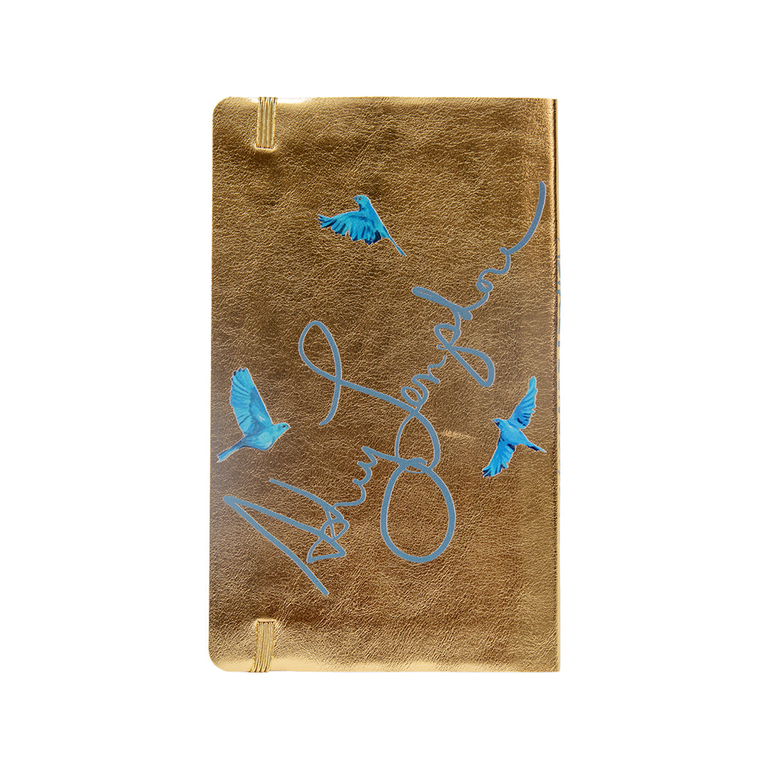 Back of gold metallic journal with Ashley Longshore’s blue signature and illustrated bluebirds in flight.