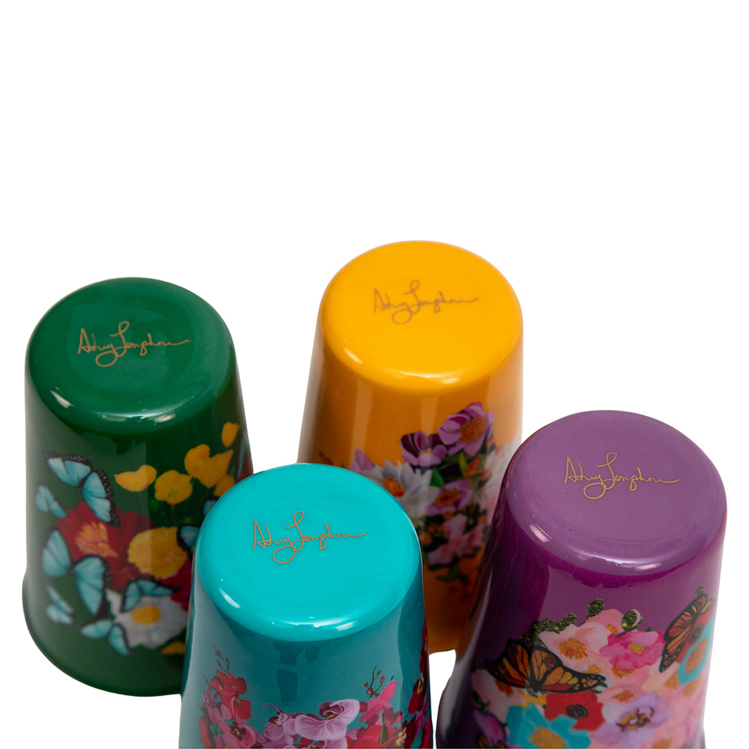 Four colorful tumblers with floral designs and a signature on a white background