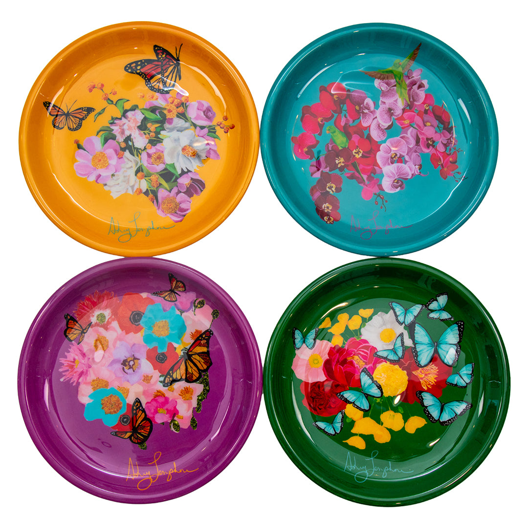 Four colorful plates with floral and butterfly designs on a white background