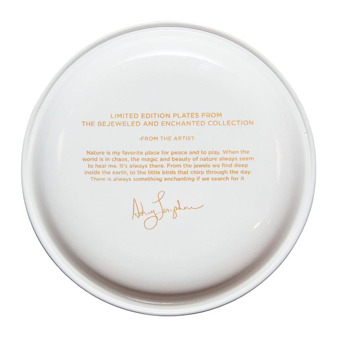 White plate with gold text and signature on a white background