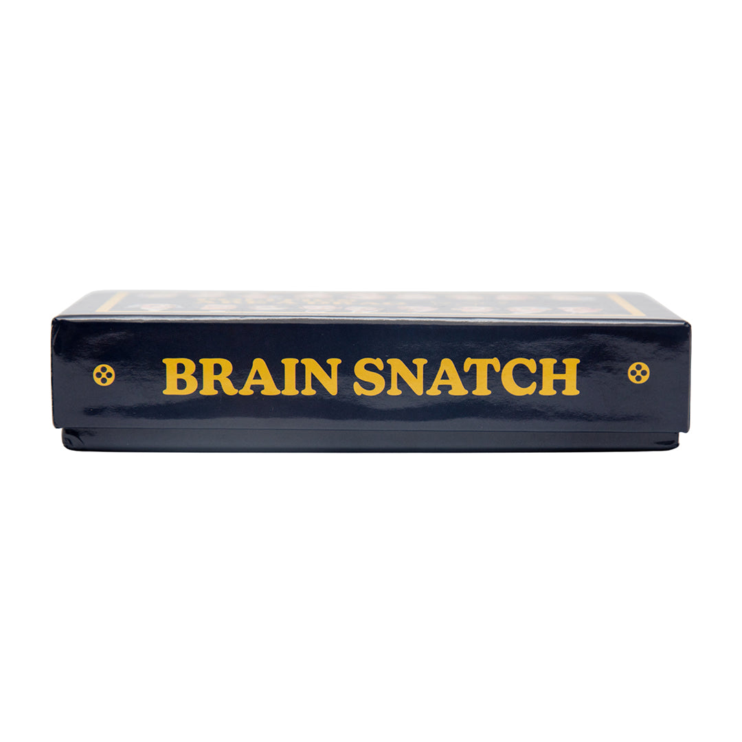 Detail shot of the Politics Are a Drag Brain Snatch game box with gold foil lettering and Ashley Longshore signature branding.