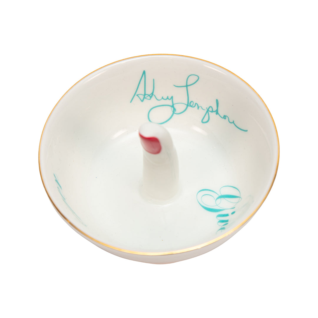 Ashley Longshore porcelain middle finger ring dish with red nail and turquoise script text reading “Give Um the Finger” along with Ashley Longshore’s signature.
