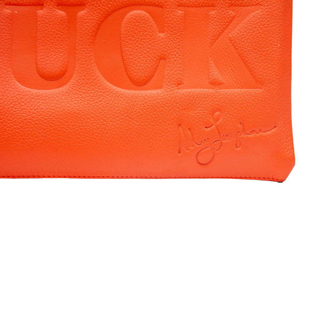 Close-up of the bag showing the embossed word and Ashley Longshore’s signature on textured orange leather.
