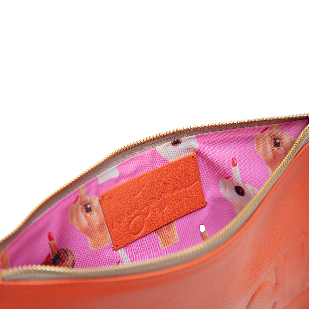 Inside of the bag showing bright pink lining with illustrated hands flipping the middle finger and leather logo patch.
