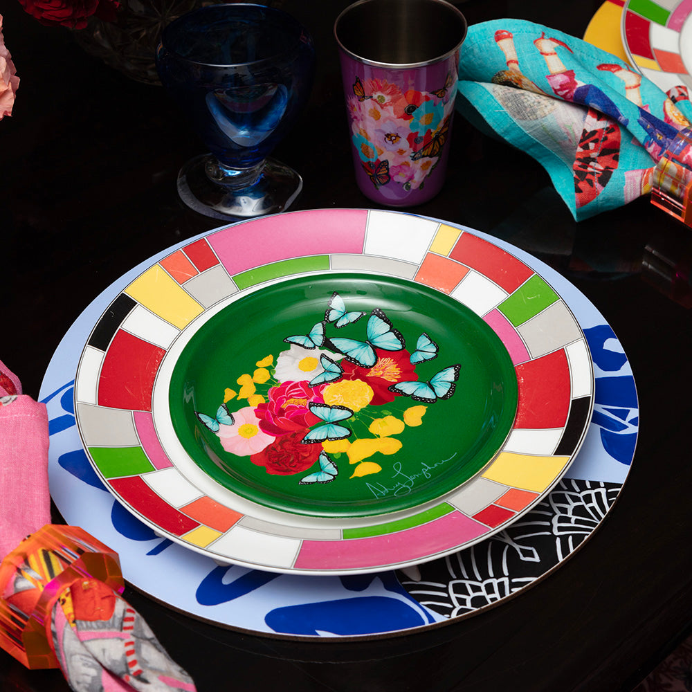 Colorful green enamel plate with floral and butterfly design on a black surface