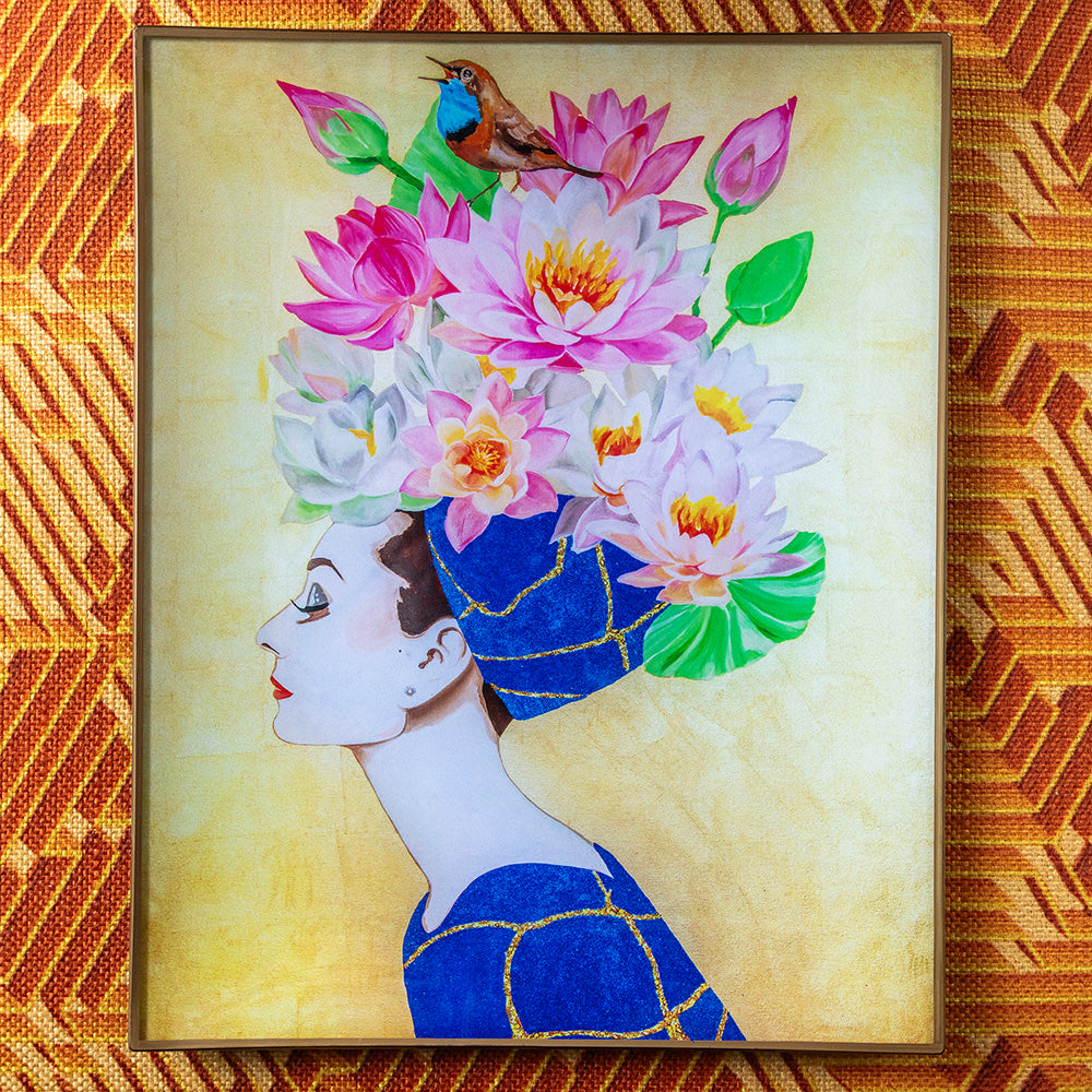 Glass deco tray featuring Ashley Longshore’s artwork of Audrey in a blue kintsugi-style gown with a crown of pink lotus flowers and a small bird perched on top, set on a geometric orange and gold textured background.