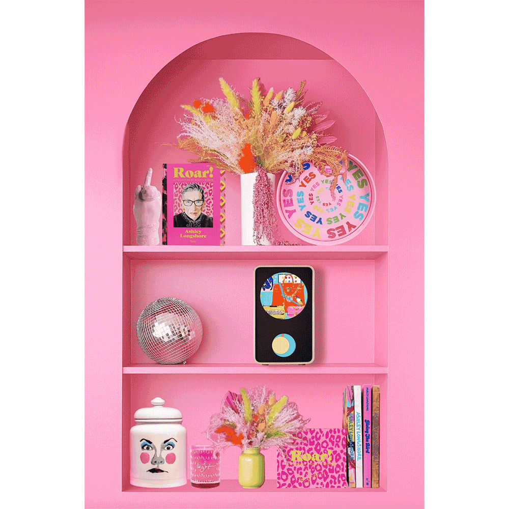 Ashley Longshore x KlydoClock digital clock with exclusive Ashley Longshore animated artwork on a pink shelf with Ashley Longshore Limited-Edition Goodies.