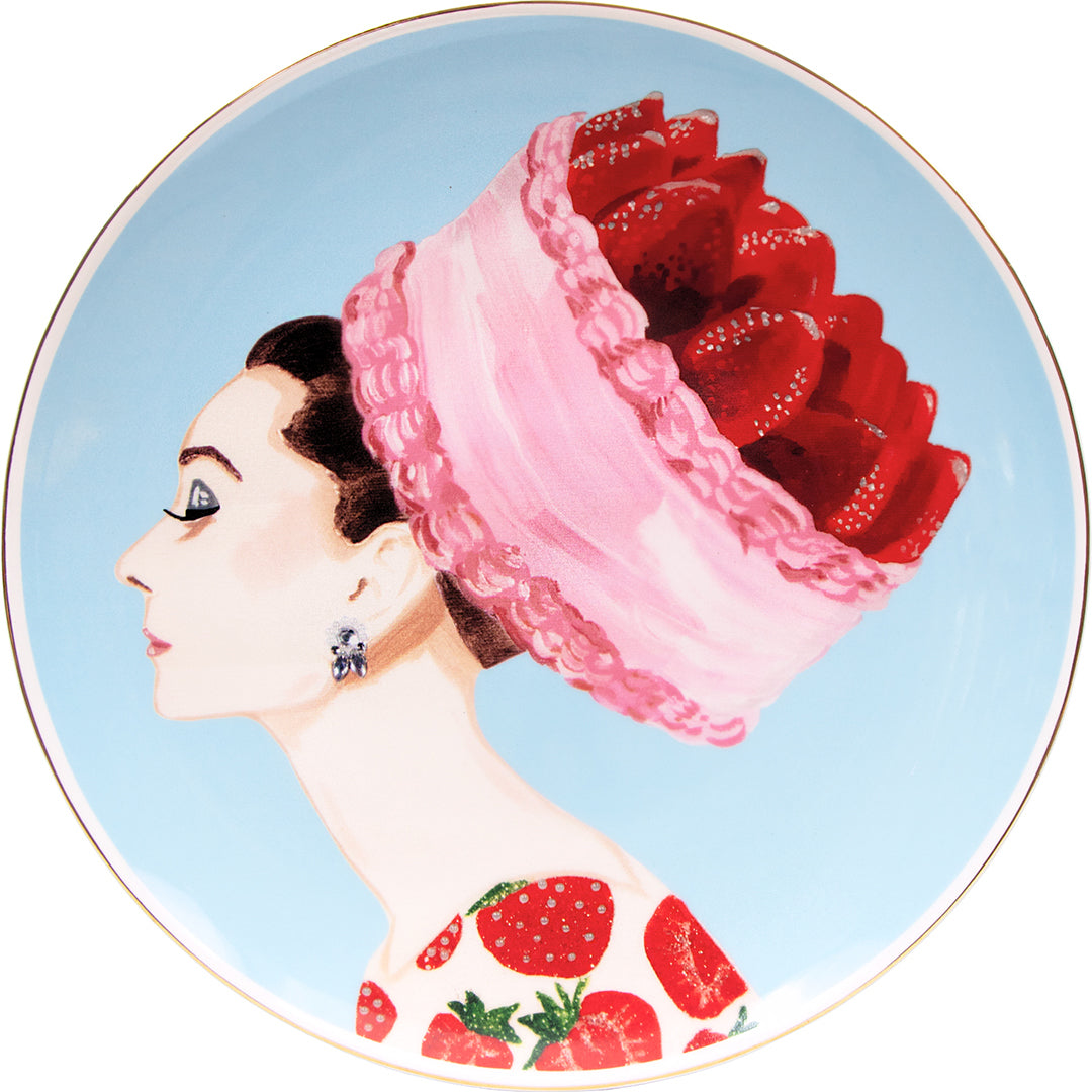 14-inch porcelain platter by Ashley Longshore featuring a side profile of Audrey wearing a pink whipped cream–style hat filled with strawberries, a strawberry-print dress, and a sky-blue background with gold rim.